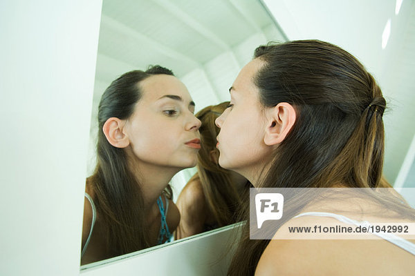 Teenagermädchen schaut sich selbst im Spiegel an  küsst ihr Spiegelbild
