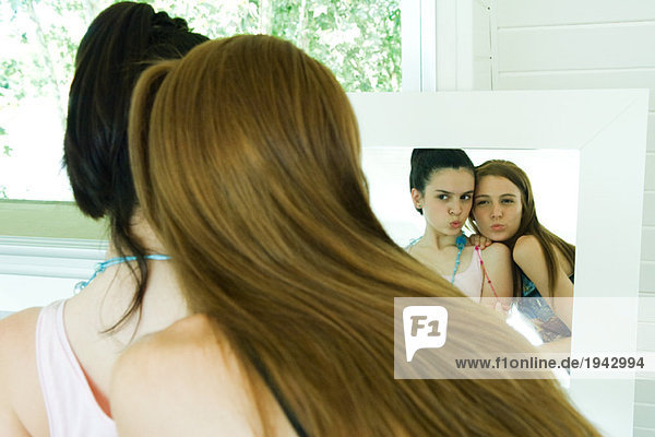 Zwei junge Freunde  die sich selbst im Spiegel betrachten  kräuseln  Rückansicht