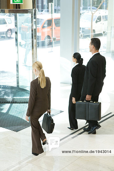 Business associates with briefcases exiting office lobby