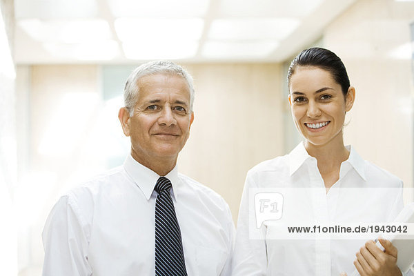 Mature businessman and young businesswoman  smiling at camera  portrait