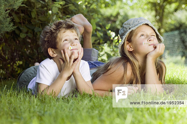 Junge und Mädchen (6-9) auf Gras liegend  aufblickend