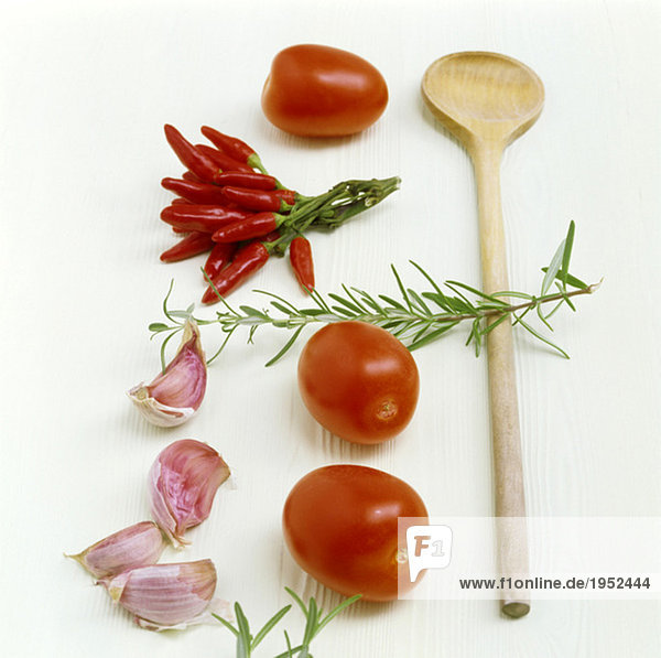 Tomaten  Chili  Knoblauch  Rosmarin und Holzlöffel auf dem Küchentisch