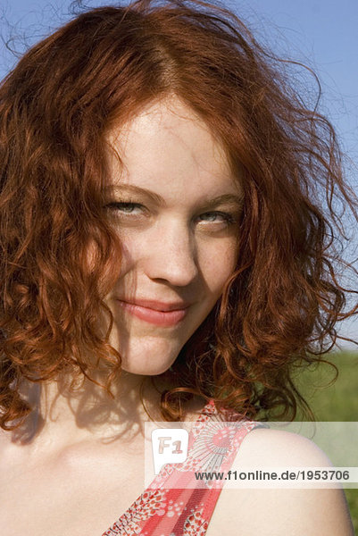 Young woman standing in meadow  smiling  portrait