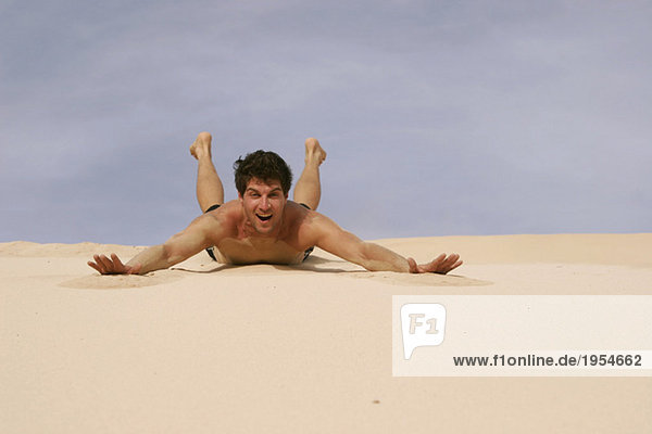 Mann gleitet auf Sand in der Wüste