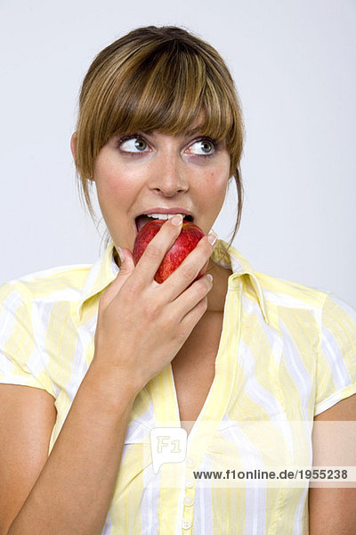 Junge Frau beißt Apfel  schaut hoch  Nahaufnahme