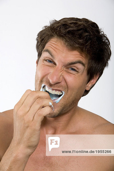 Junger Mann mit Zahnpasta im Mund