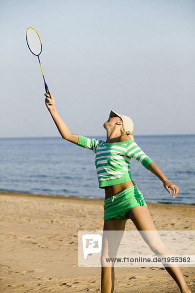 Junge Frau spielt Badminton am Strand