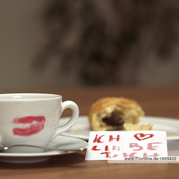 Tasse Kaffee mit Lippenstiftkuss  Croissant und I love you-sign