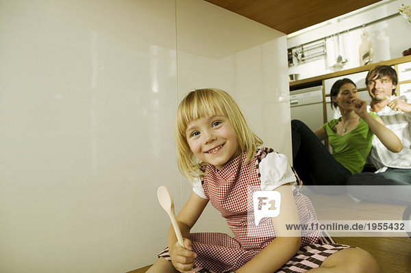 Mädchen (4-5) in der Küche  Portrait  Eltern im Hintergrund