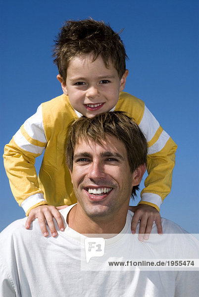 Boy (4-7) sitting on father's shoulders  portrait  close-up