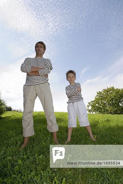 Father and son (4-7) standing in park  low angle view