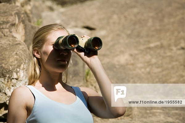 Young woman looking through field glass