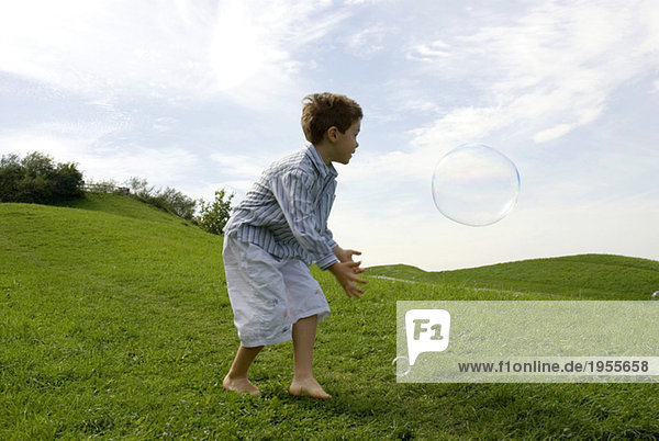 Junge (4-7) spielt mit Seifenblase  Seitenansicht