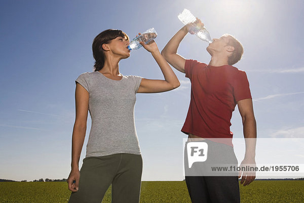 Young couple drinking from water bottle