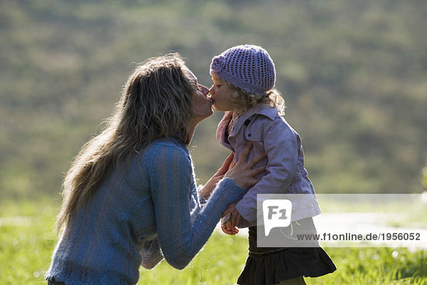 Mutter küssende Tochter  Seitenansicht