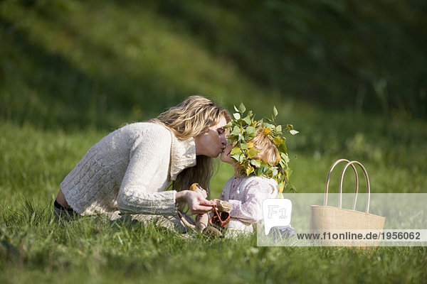 Mother and daughter in meadow,  doughter wearing wreath on head
