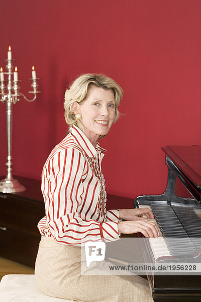 Mature woman playing piano  smiling  portrait
