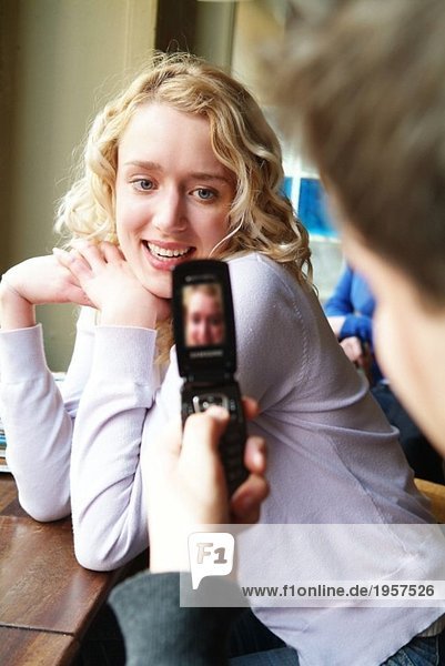 Ein Typ macht Fotos von einem Mädchen mit einem Handy.