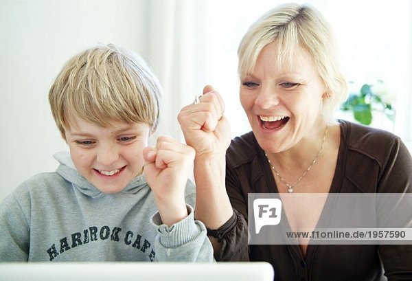 Mutter und Sohn jubeln vor dem Computer