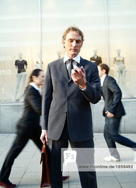 Businessman stopping and looking at his phone