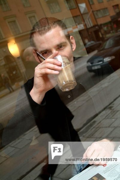 Mann trinkt Kaffee und schaut hinaus.