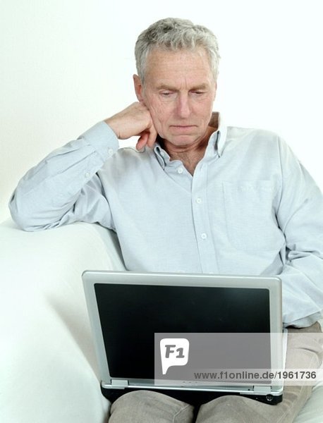 Älterer Mann im Sofa mit Laptop