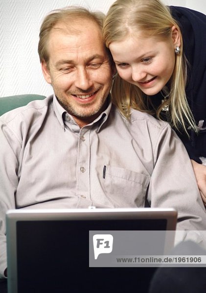 Vater und Tochter schauen auf den Bildschirm