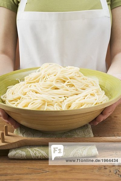 Frau hält Schüssel mit gekochten Spaghetti