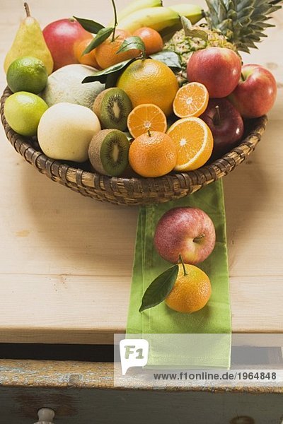 Verschiedene frische Früchte im Korb auf Holztisch