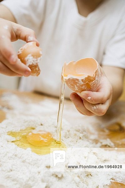 Nudelteig zubereiten: Kind schlägt Ei auf