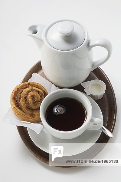 Kaffeetasse  Zimtschnecke  Sahne und Kaffeekanne auf Tablett