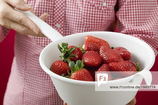Frau hält Seiher mit Erdbeeren