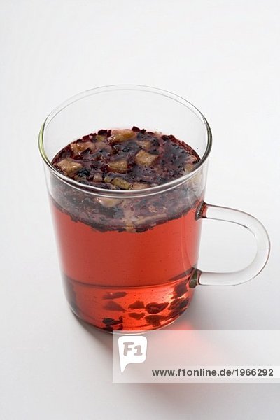 Fruit tea with tea leaves in glass cup