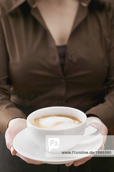 Frau hält grosse Tasse Cappuccino