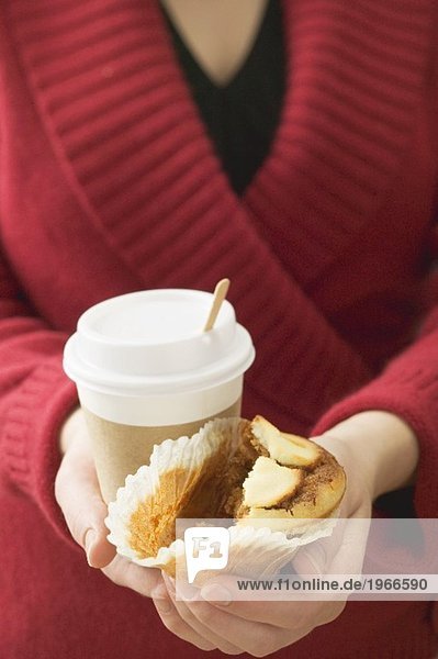 Frau hält Muffin und Kaffeebecher