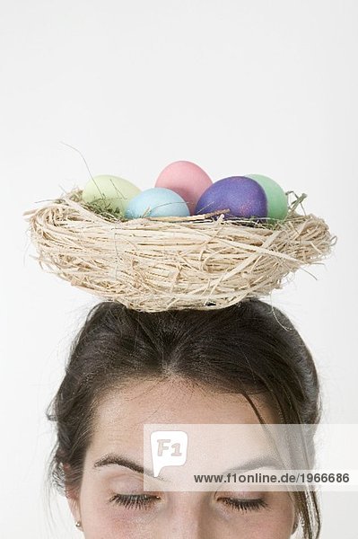 Frau trägt Korb mit gefärbten Eiern auf dem Kopf