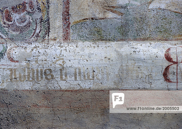 Detail eines alten Freskos mit Inschrift auf Steinwand