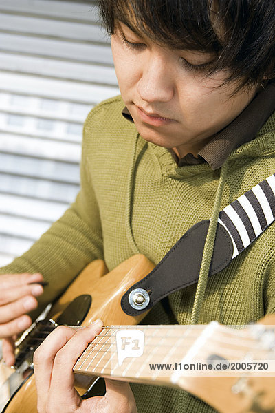 Junger Mann  asiatisch  spielt auf E-Gitarre