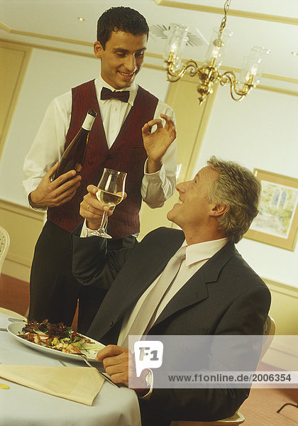 Mann im Restaurant  Kellner serviert Wein