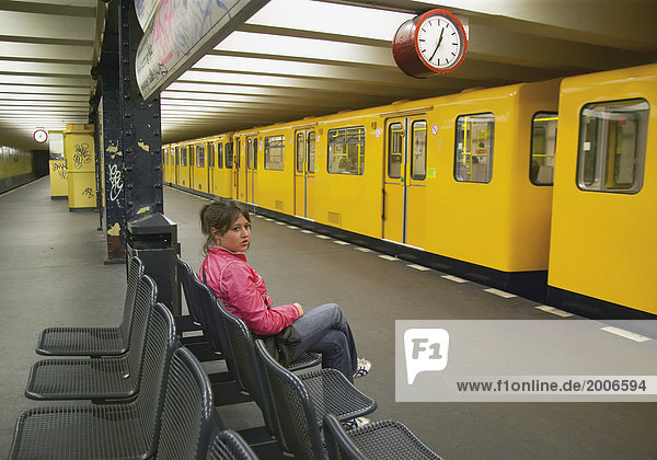 Junge Frau sitzt allein in U-Bahnhof