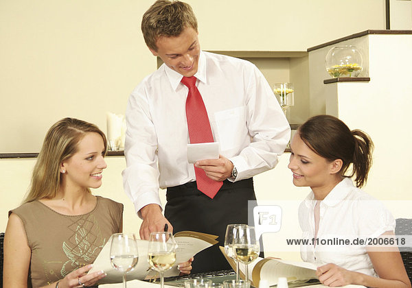 Zwei Frauen sitzen im Restaurant  bestellen bei Kellner