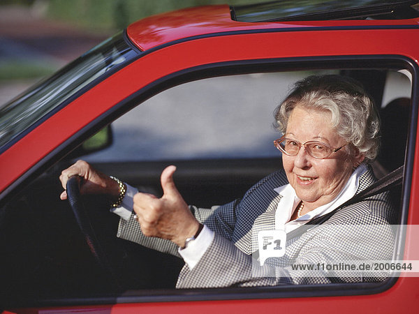 Seniorin am Steuer eines Autos  Gestik Daumen hoch