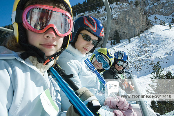 Young skiers on chair lift  smiling at camera