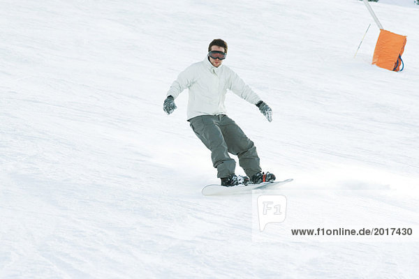Junger Mann Snowboarden auf der Piste  volle Länge
