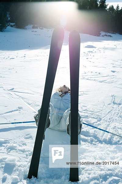 Young skier lying on back in snow  view through skis