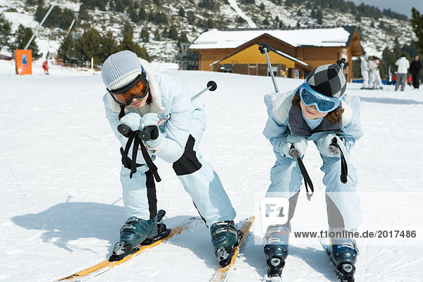 Two young skiers crouching together  looking at camera