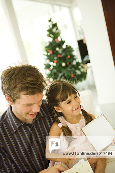 Vater und Tochter eröffnen gemeinsam  Weihnachtsbaum im Hintergrund