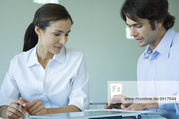 Two business associates sitting side by side  discussing document together