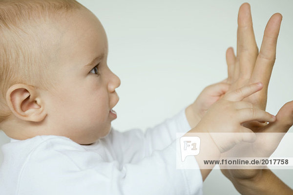 Baby greift nach der Hand der Mutter  Profilansicht  Nahaufnahme