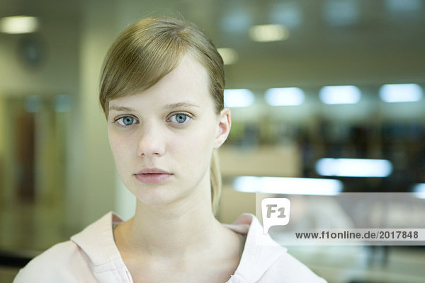 Junge Studentin in der Bibliothek mit Blick auf Kamera  Kopf und Schultern